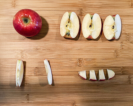 different-size pieces of apple cut-up on a cutting board